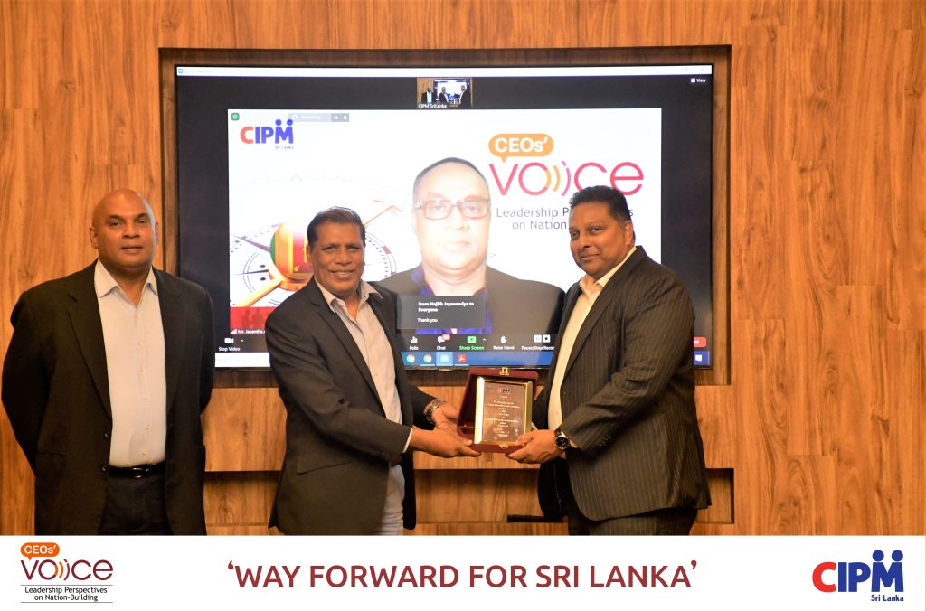 Mr. Priyantha Talwatte receiving the token of appreciation from Mr. Ken Vijayakumar, Vice President of CIPM SL with Dr. Samitha Perera standing beside and Mr. Jayantha Amarasinghe on the screen 